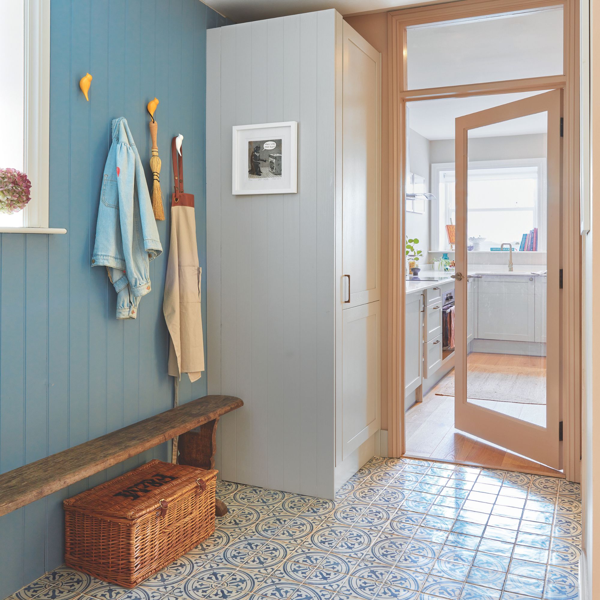 Hallway storage area with a bench seat and hooks on the wall with coats and aprons hanging from it