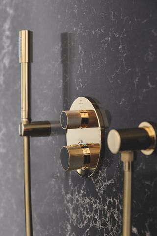 Grohe Spa brass shower fittings on black wall