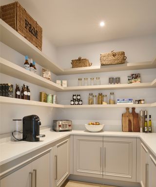 inside of walk in pantry designed with cream base units, worktop and open cream shelving around three walls