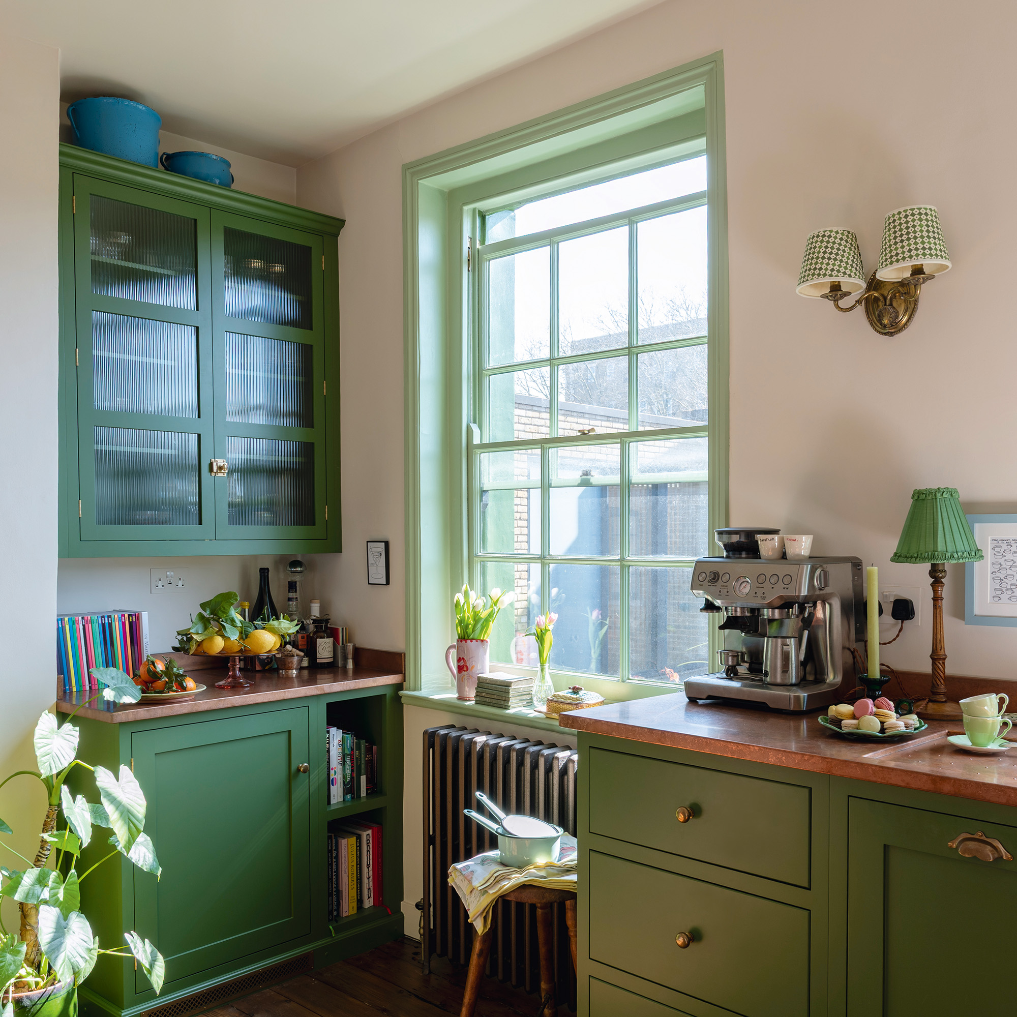 traditional kitchen with green cabinetry and woodwork, cream walls and wooden floors in a 17th-century london maisonette