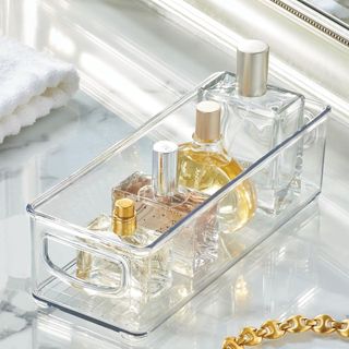 Clear plastic bin with perfume bottles stacked neatly inside
