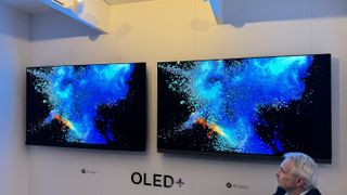 Philips OLED909 and OLED908 TVs side-by-side, with both screens showing an explosion of colour