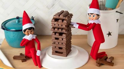 Elf figures creating a chocolate tower in the kitchen, one of the best Elf on the Shelf ideas