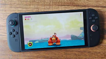 Nintendo Switch 2 on woodgrain surface with Donkey Kong Bananza gameplay on screen.