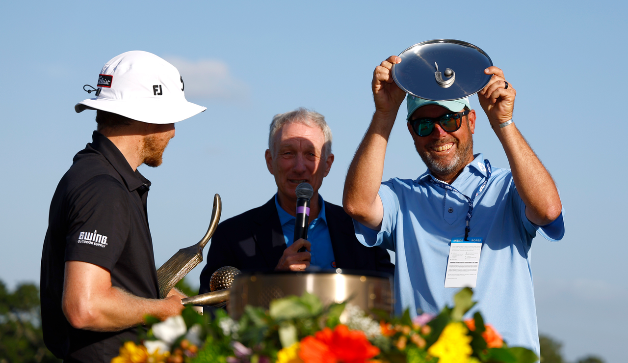 Peter Malnati&#039;s caddie holds a trophy after Malnati&#039;s victory at the Valspar Championship