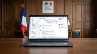Microsoft Teams running on a Windows 11 laptop in a mockup of a French government office. 