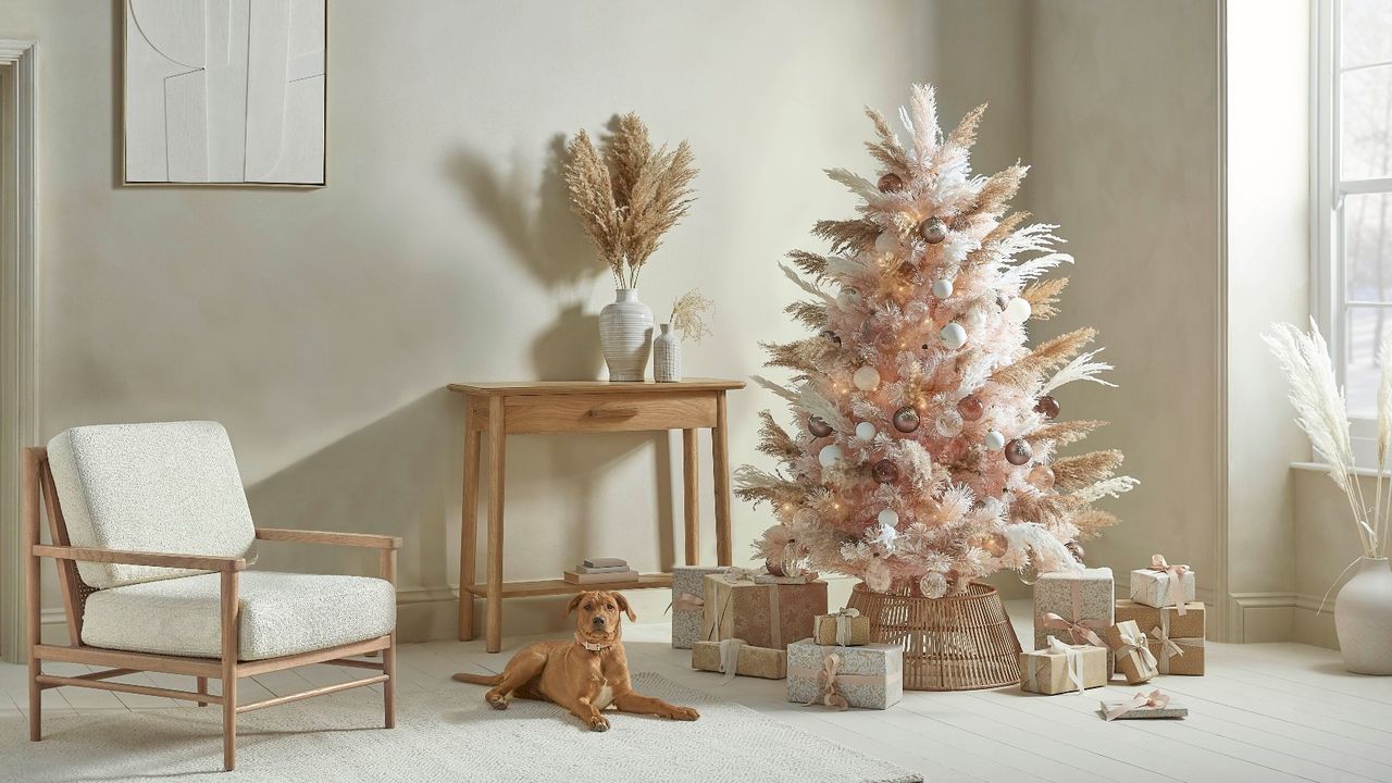 Cox &amp; Cox Pampas Dreams Dusky Blush Christmas tree in a neutral living space next to a table and a dog