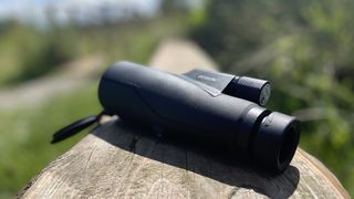 Python 12x52 Range Master Ultra HD Monocular on a wooden log in a park