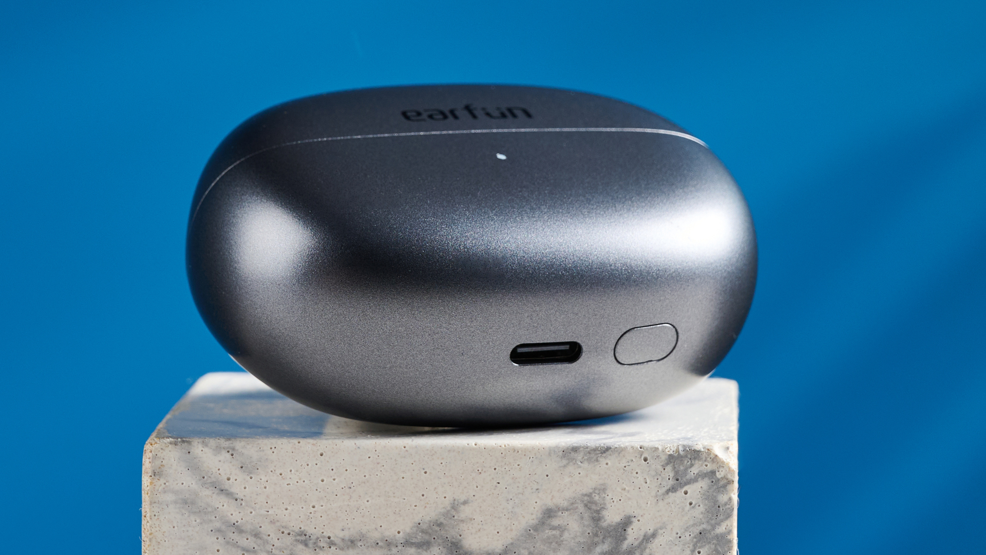 EarFun Clip open-earbuds photographed in front of a blue background.