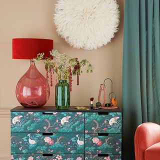 chest of drawers with wallpaper and lamp with kitsch wall pompom