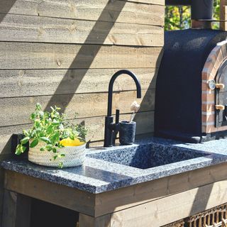 outdoor worktop and sink area with wooden fencing and pergola