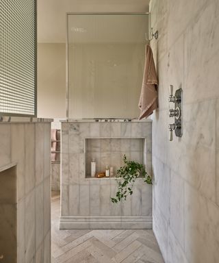 walk in tiled shower cubicle with shelves inset into half height walls