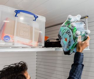 ceiling mounted rack in garage with man reaching up to take bottles next to plastic tub