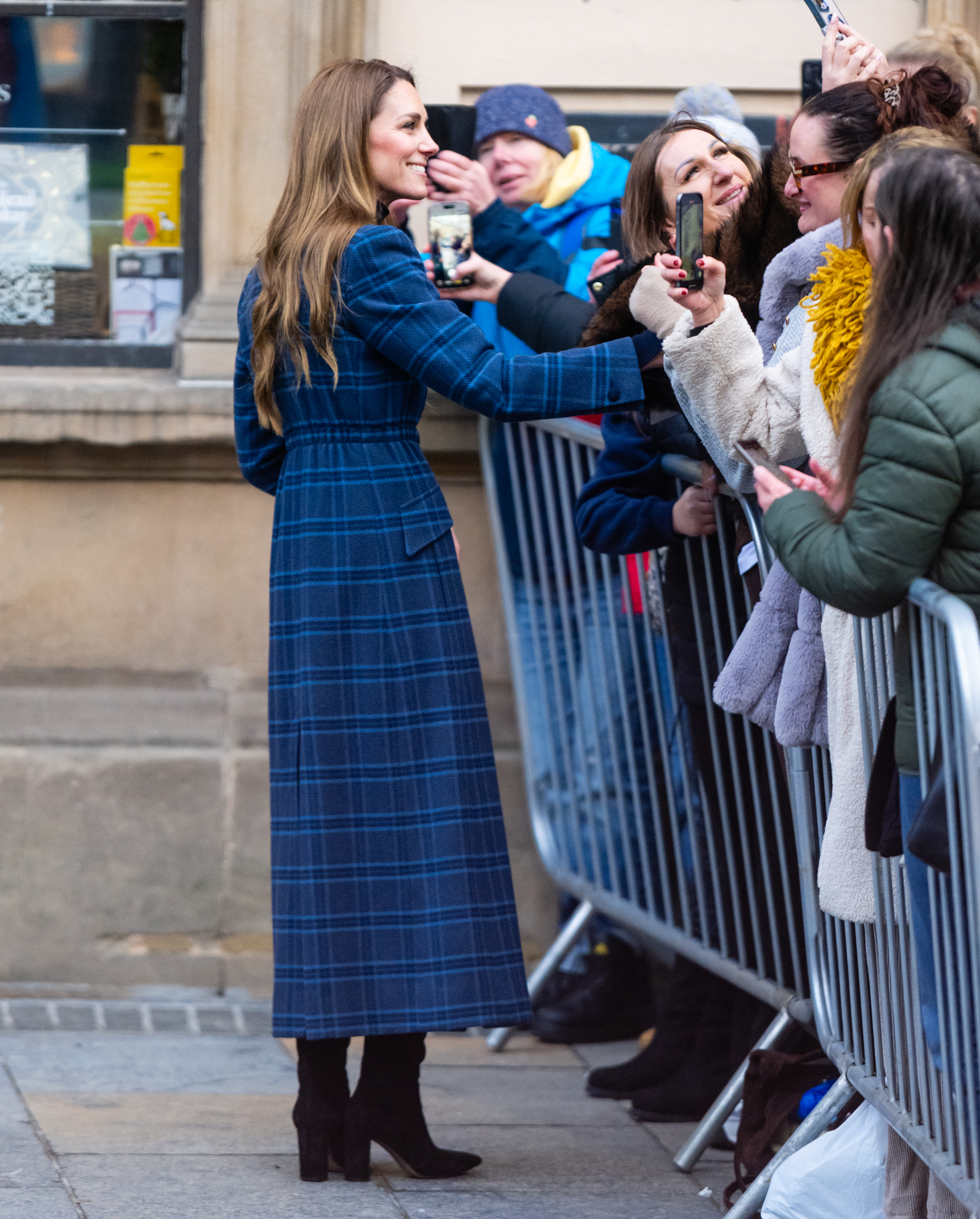 Princess Kate wearing a blue plaid coat greeting fans