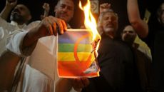 Supporters of Iraqi Shia cleric Moqtada Sadr burn a poster depicting an LGBTQ+ flag during a protest in Karbala on 29 June 2023