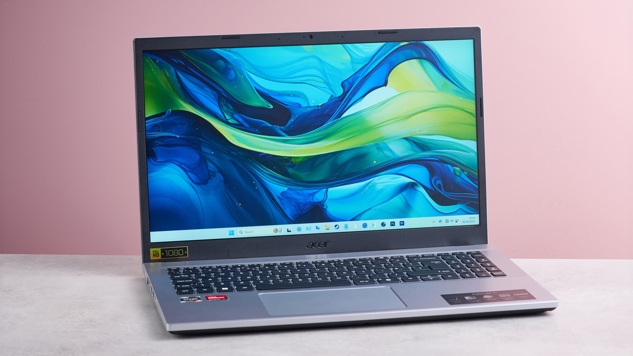 Three-quarter view of Acer Aspire Go 15 open on desk, with pink wall in background