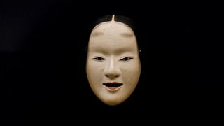 A noh mask on a black background