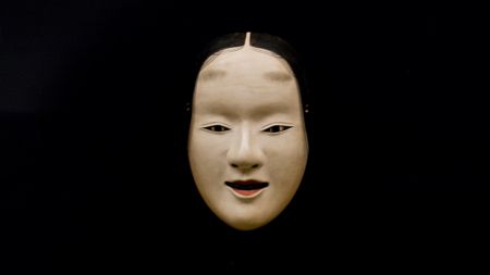A noh mask on a black background
