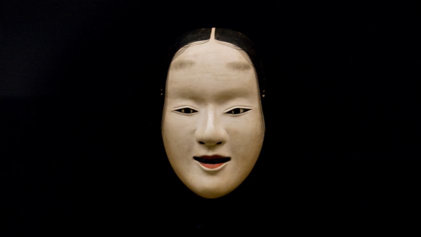 A noh mask on a black background