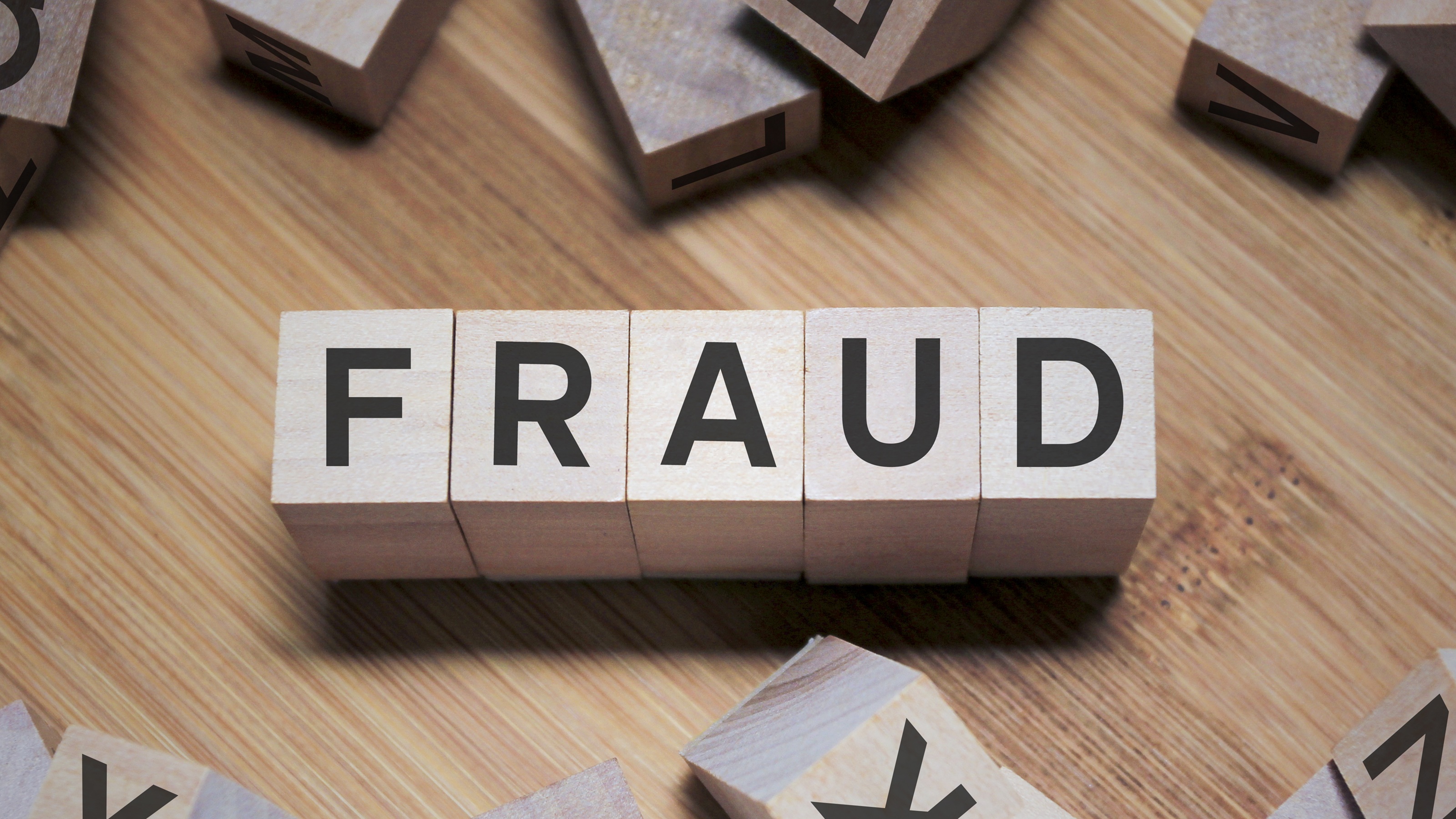 The word "fraud" spelled out in wooden blocks.
