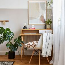 Home office in spare room with wooden desk and chair and boho-style accessories