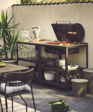 Ikea GRILLSKÄR charcoal barbecue in external courtyard with green children's toy on floor