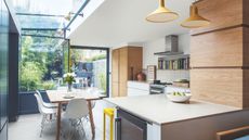 Kitchen diner extension with partly glazed roof, natural wood cabinets and view to garden