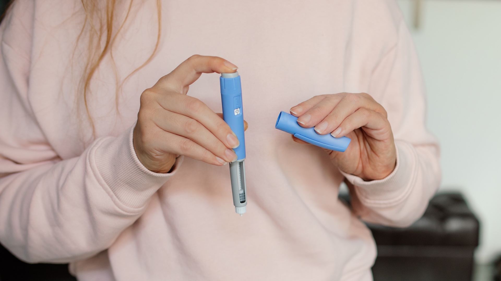a close-up of a woman&#039;s hands opening a semaglutide injector