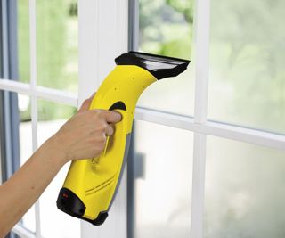 Someone using a karcher to clean a window