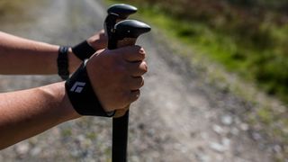 A pair of hands hold the grips of some Black Diamond Pursuit Trekking Poles