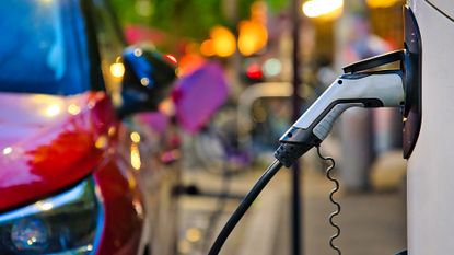 EV charger with red electric car in background