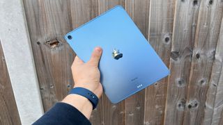 Image shows someone holding out the iPad Air, showing it from the back of the device.