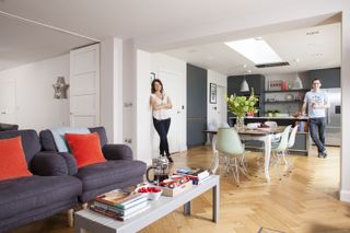 open plan modern kitchen-diner and living area with pastel chairs and wooden flooring