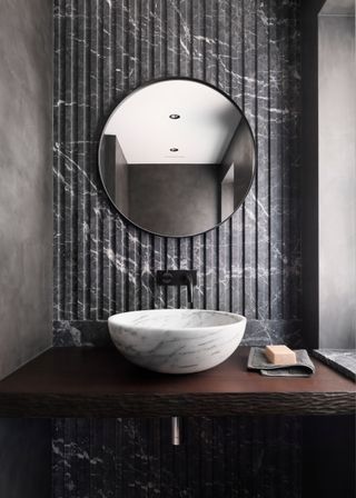 A bathroom with dark marble accents and white marble basin