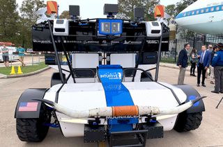 head-on view of a blue and white rover sitting on a sidewalk, with the horns of a texas longhorn bull mounted to its front bumper