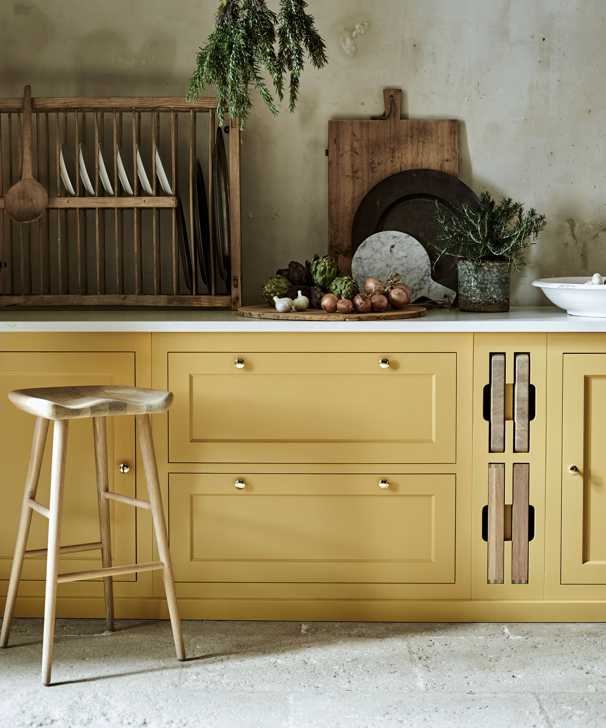 Painted kitchen cabinet ideas in mustard yellow with stone flooring, textured walls and wooden accents.