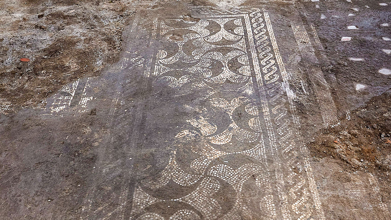 archaeologists work at an ancient Roman site revealing mosaic floors and frescoed walls of a villa