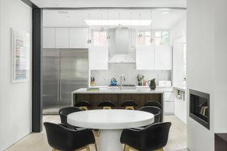 White kitchen with white dining room table and black chairs at the OverUnder House in Boston