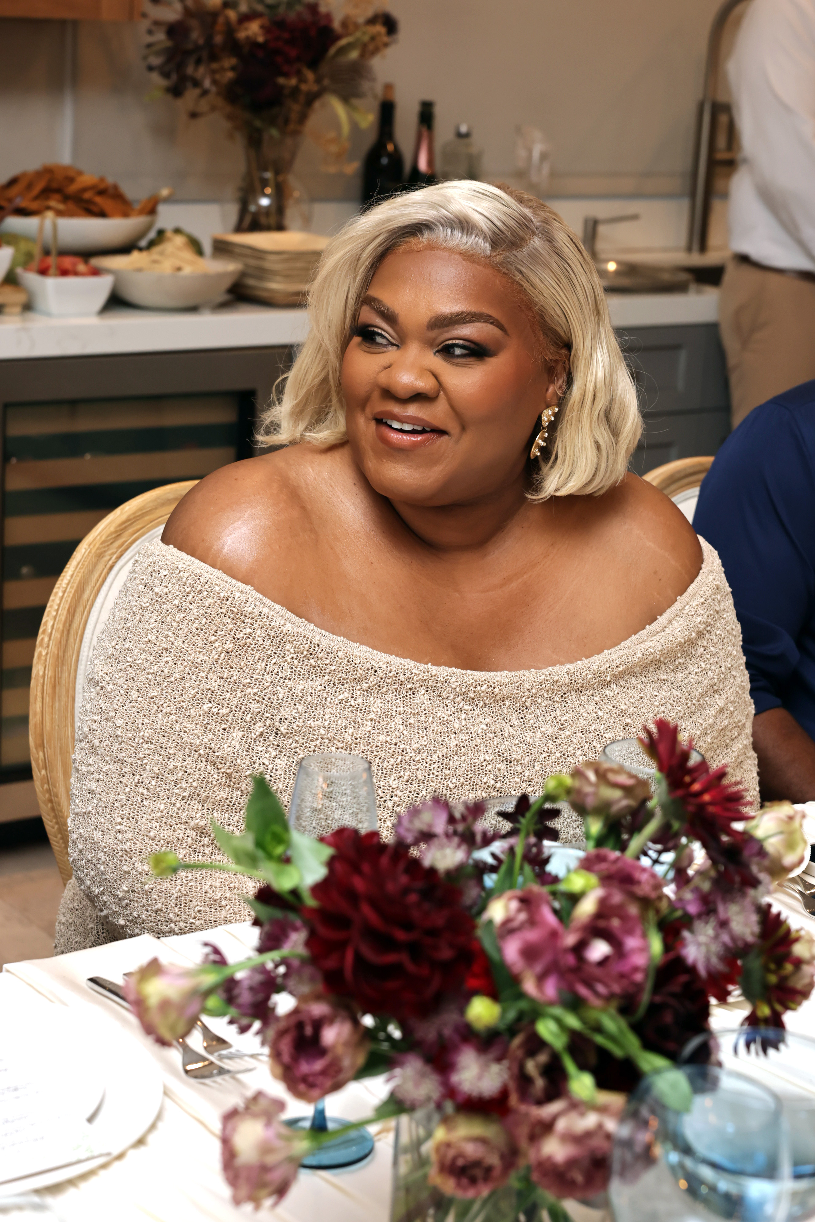 a black woman with platinum blonde hair pictured seated at a dining table