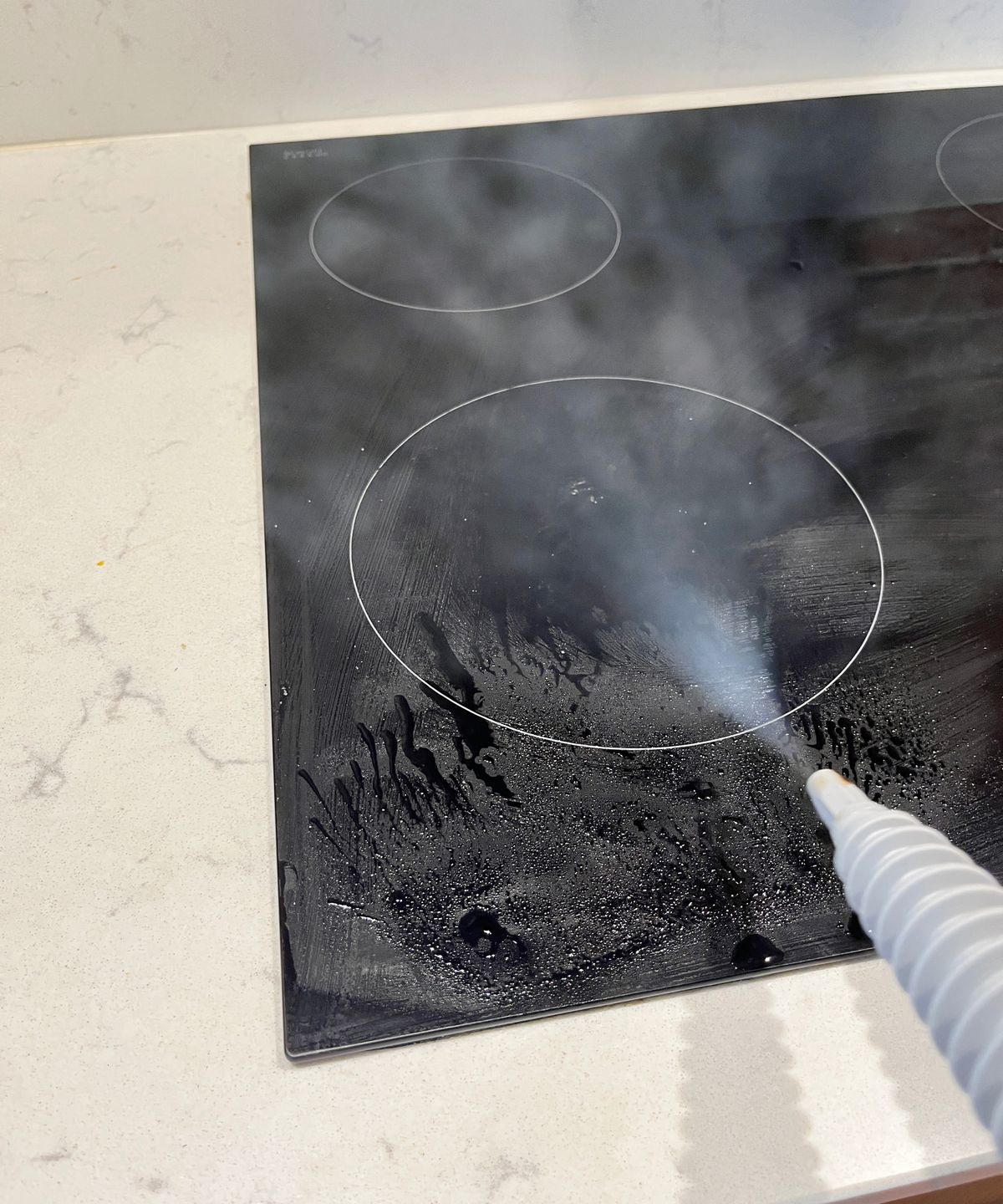 steam cleaner being used on black induction hob