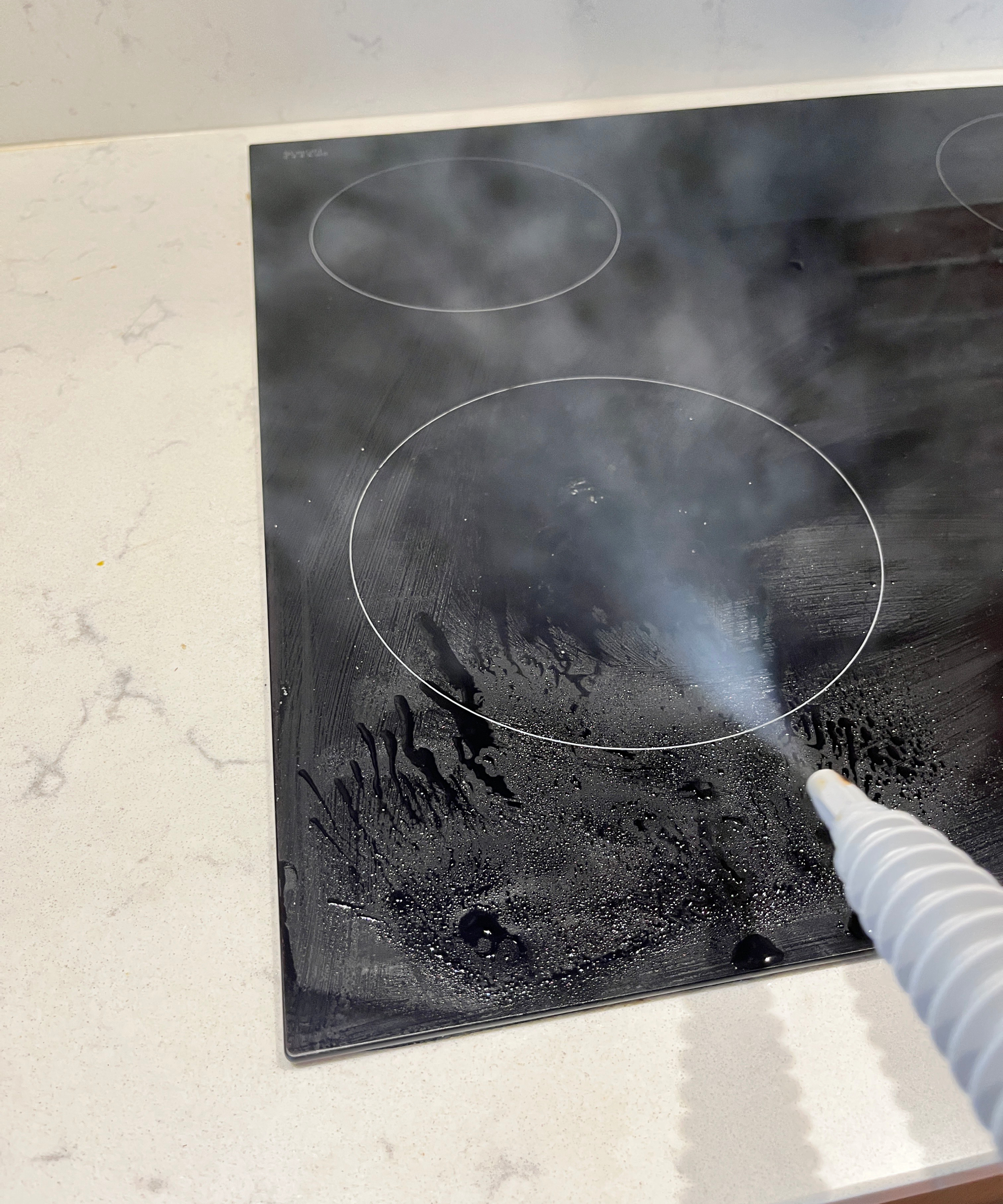 steam cleaner being used on black induction hob