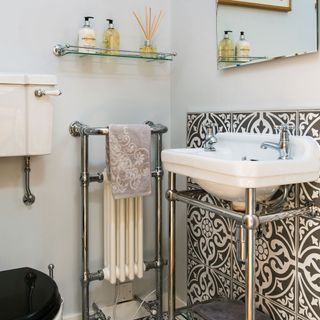 bathroom with wash basin white and designed tile wall silver pipes
