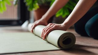 A woman rolling up her yoga mat