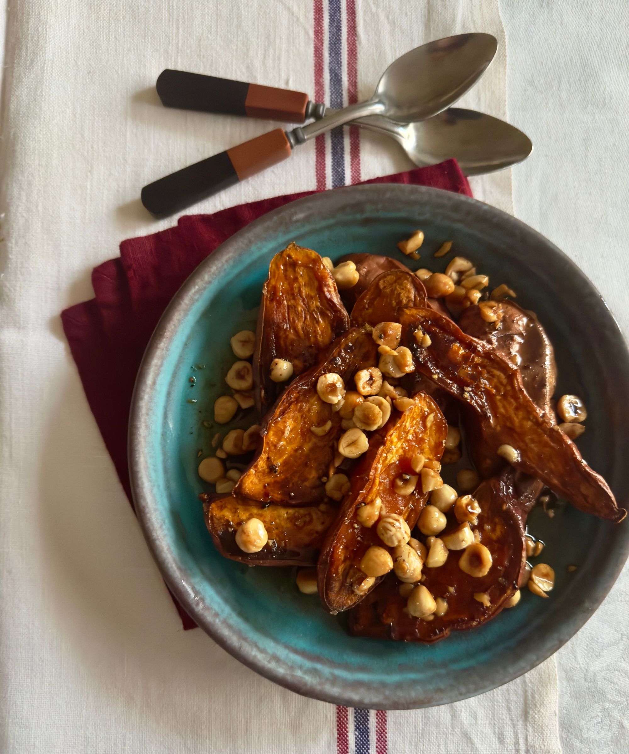 Sweet potato and nut dish in a green bowl on a red napkin and striped tablecloth