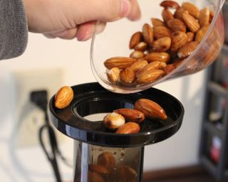 Camryn Rabideau juicing a cup of soaked raw almonds