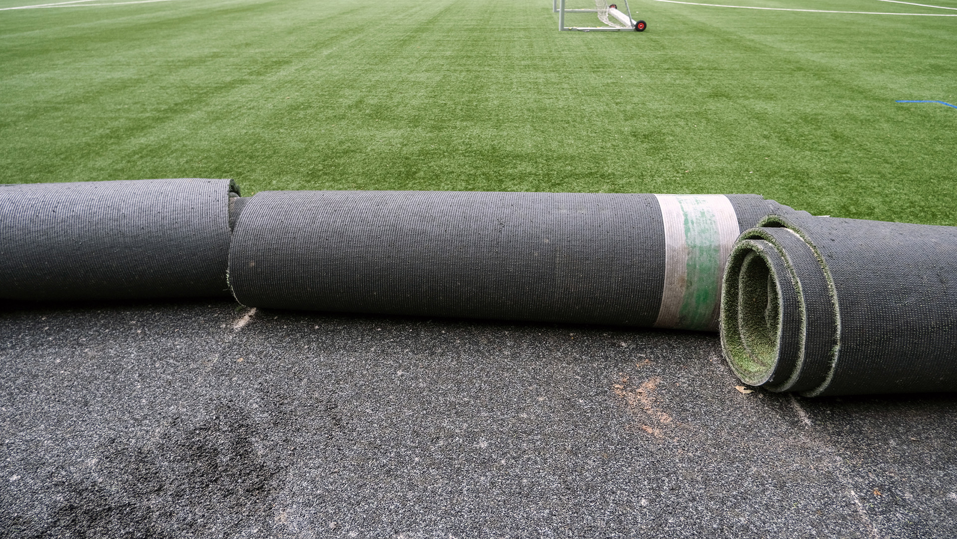 Rolls of turf being unrolled onto a lawn.