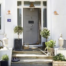 house with white wooden door brass light fittings and stone urns