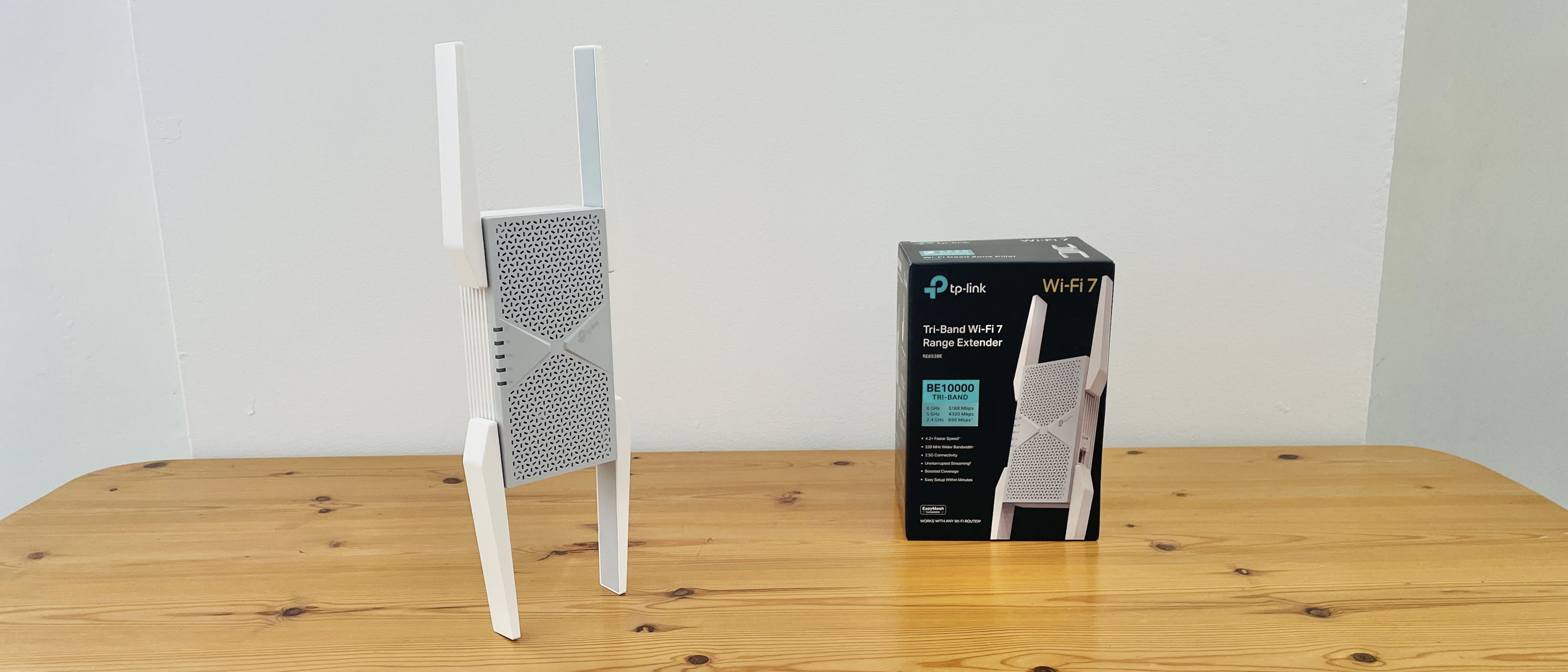 TP-Link BE10000 Wi-Fi range extender on wooden desk