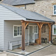 Grey weatherboard annexe to period stone house
