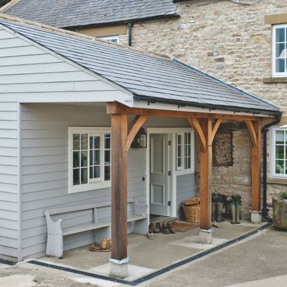 Grey weatherboard annexe to period stone house